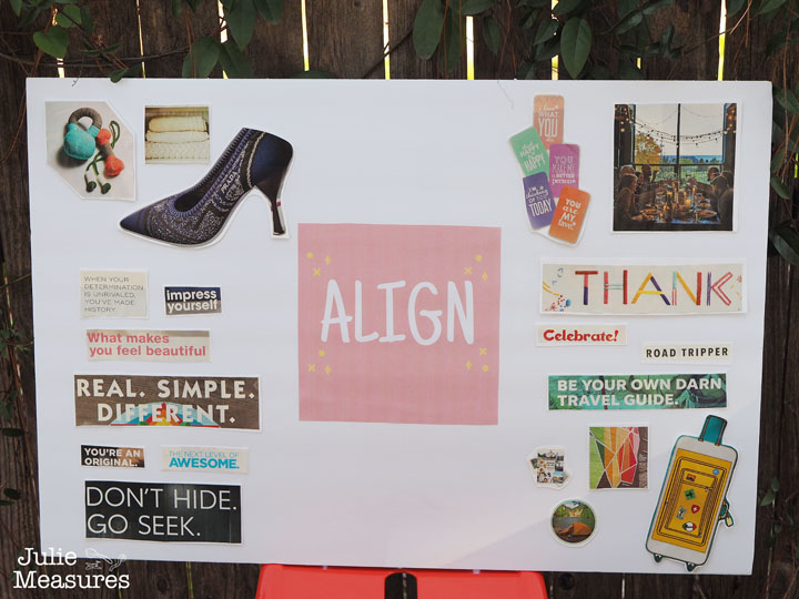 A vision board white cutouts in front of a wood fence outside.