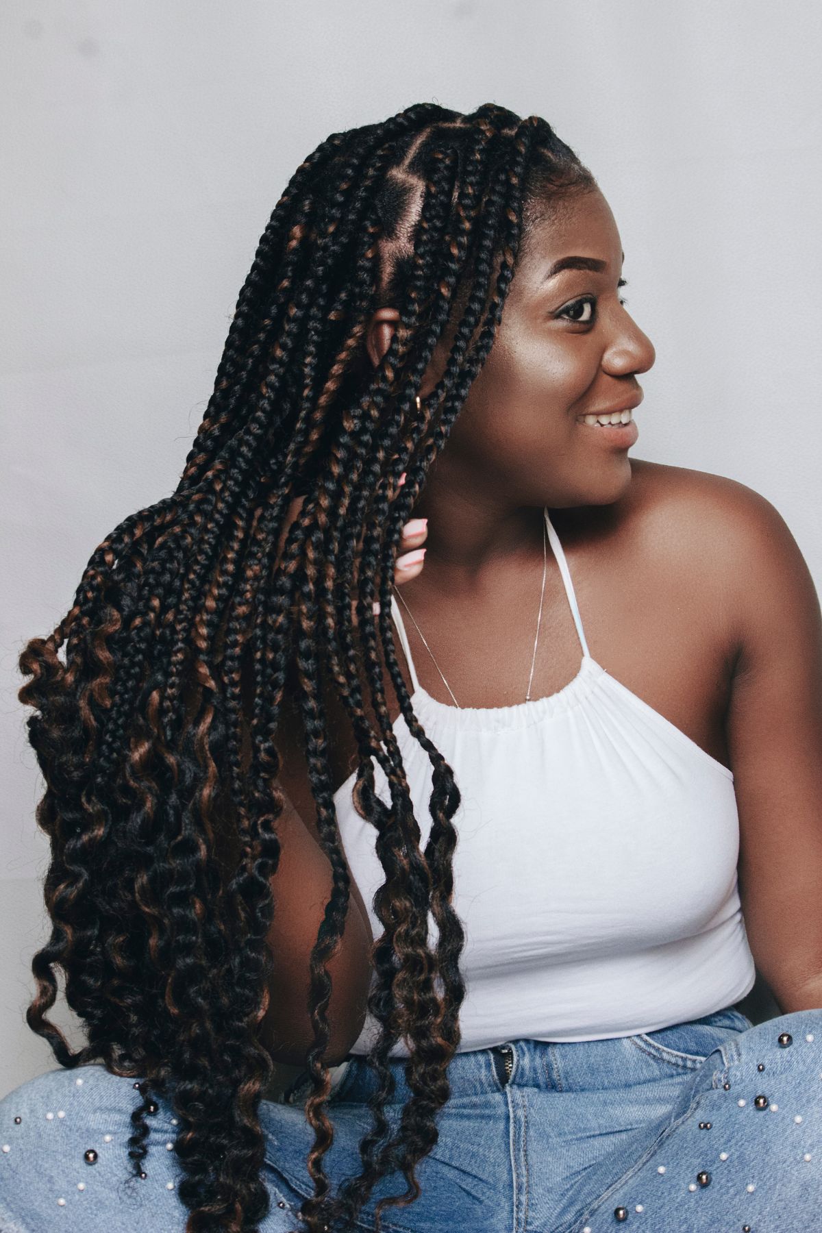 A black woman with medium box braids with curly ends.