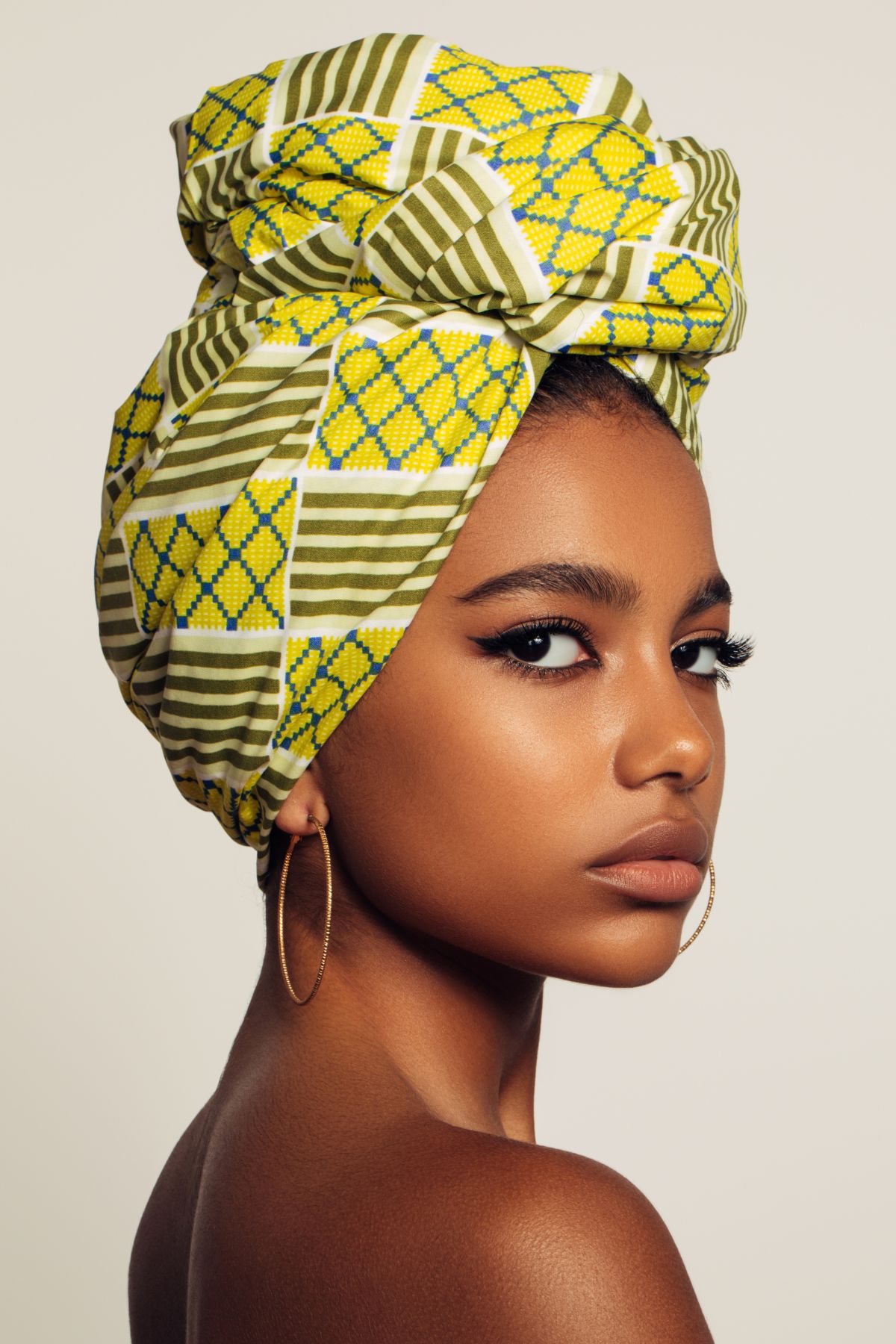 A black woman with a yellow scarf bun.