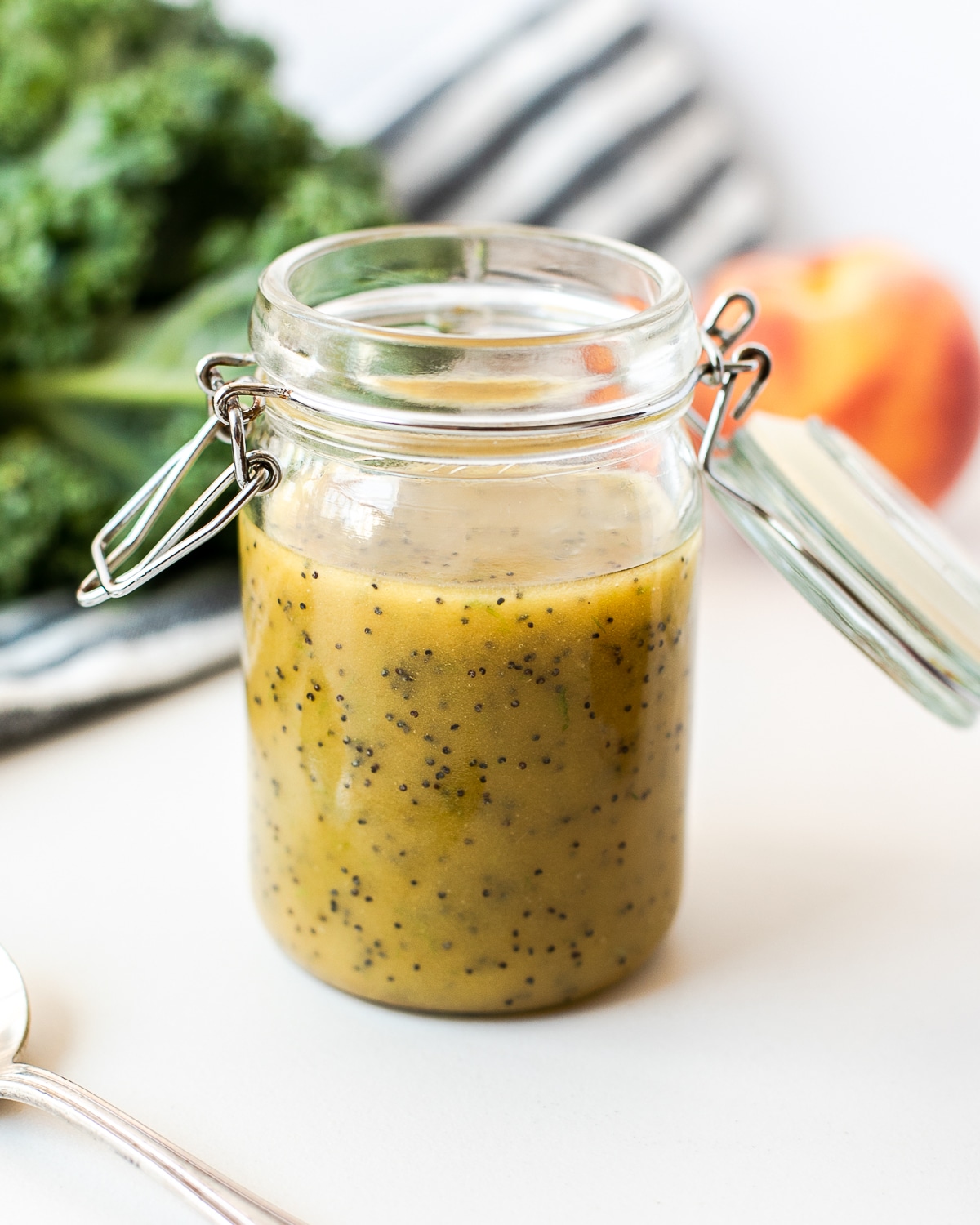 Poppy seed vinaigrette dressing in a mason jar with a plate of salad in the background.