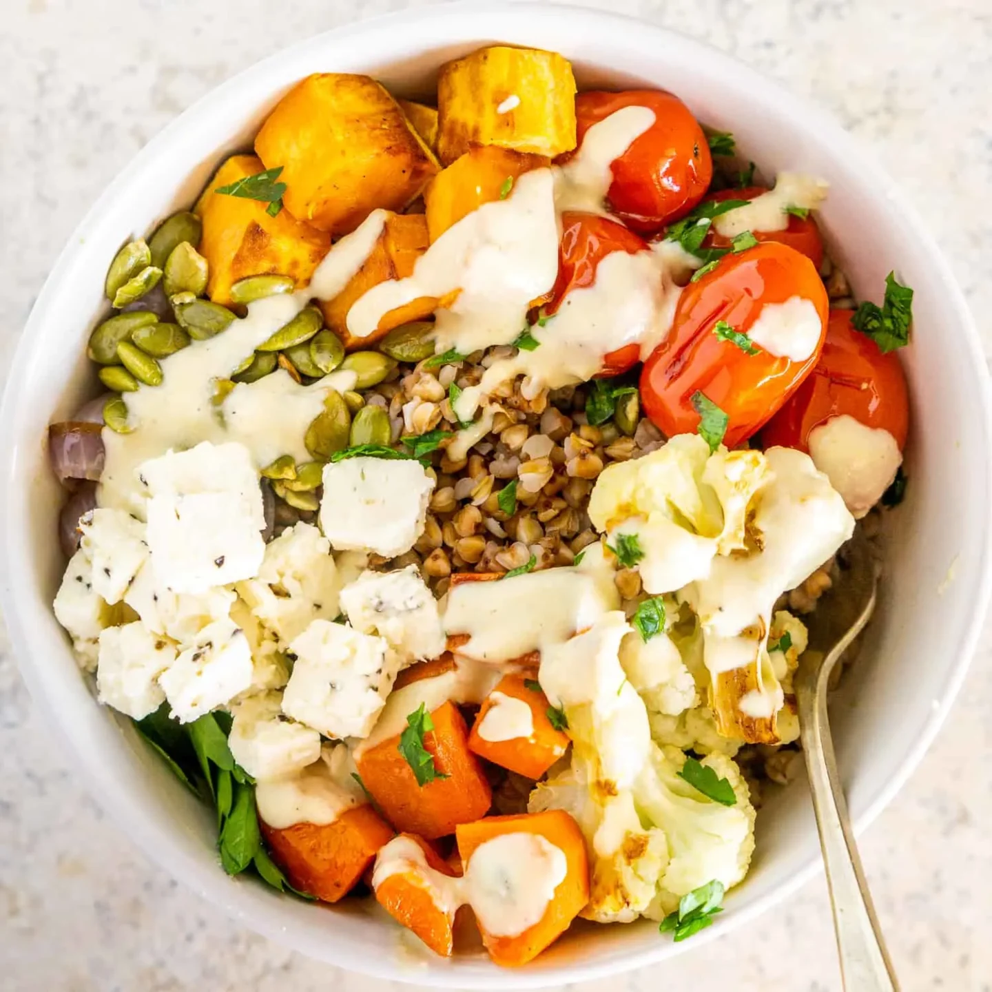 Meal prep bowl with roasted veggies and tahini sauce.