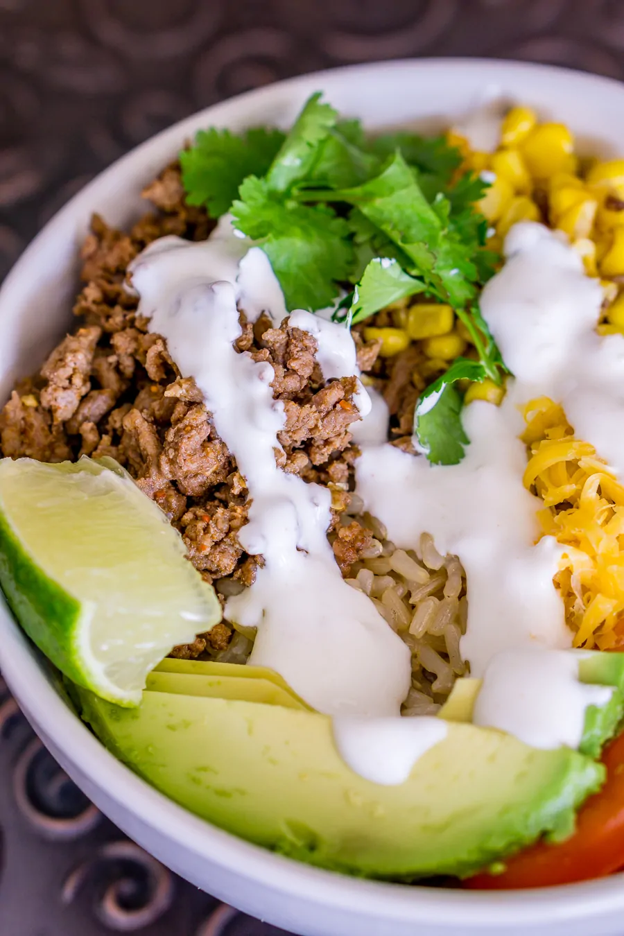 Taco rice bowl with ground beef, avocado, and cream.