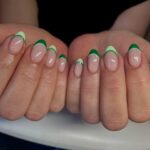 Almond French tip nails with light and dark green stripes.