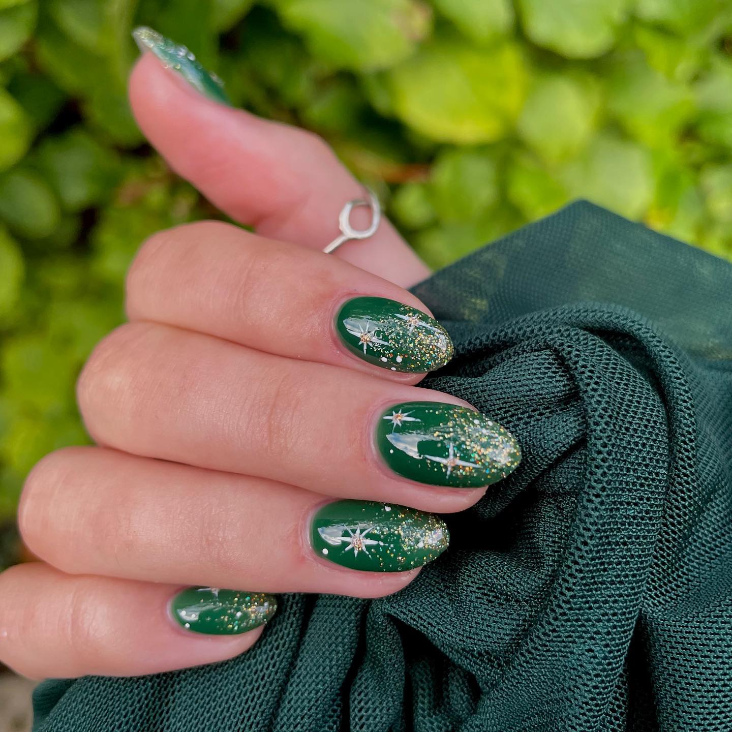Deep green almond nails with sparkles.