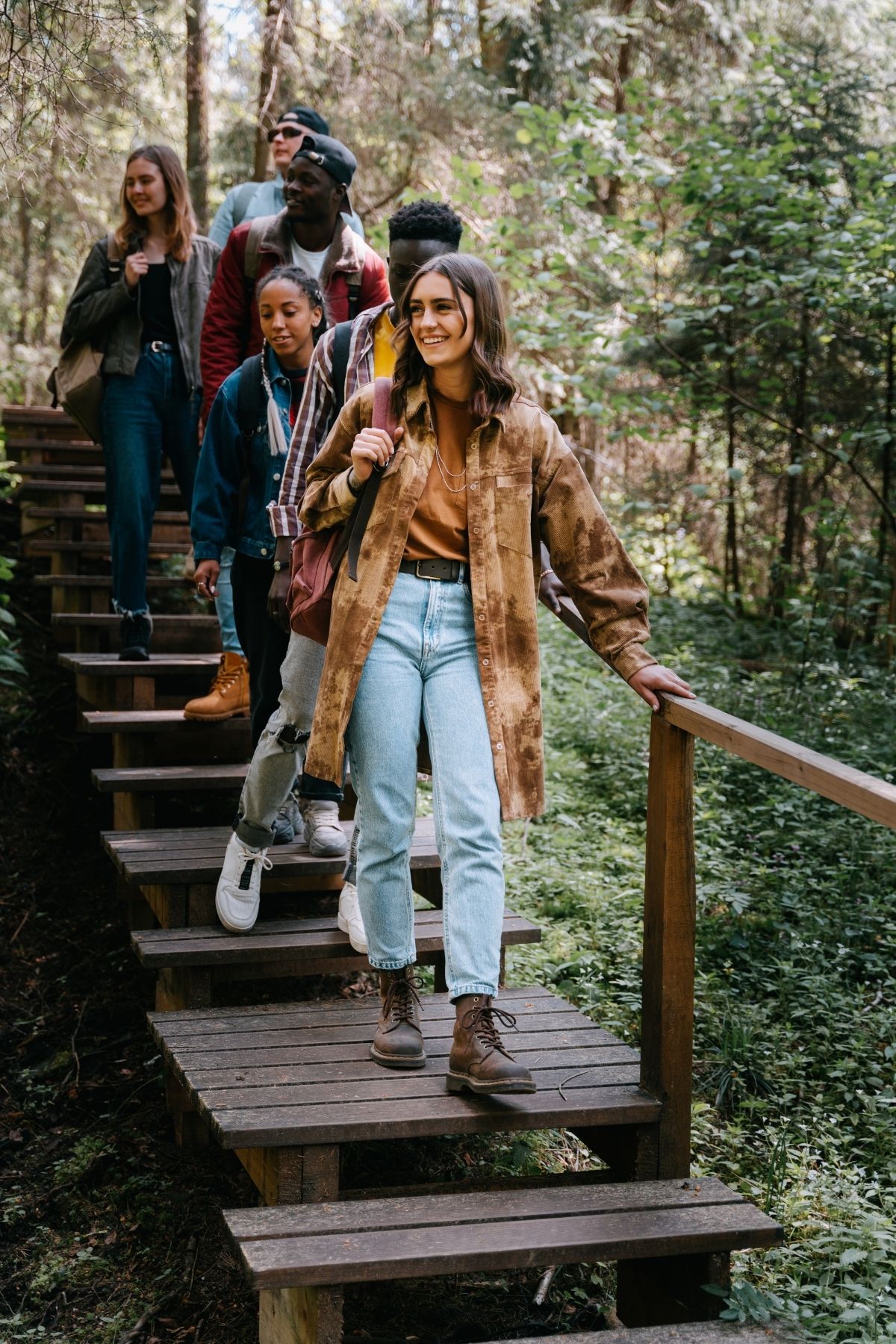 Women walking down steps on an outdoor walking trail in a woodsy area.