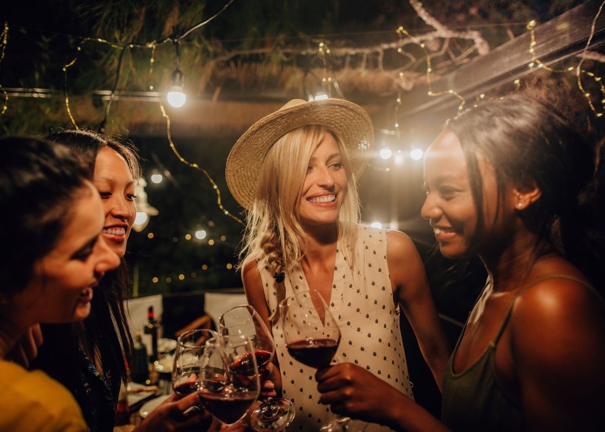 Women talking and sipping wine outside in the city.