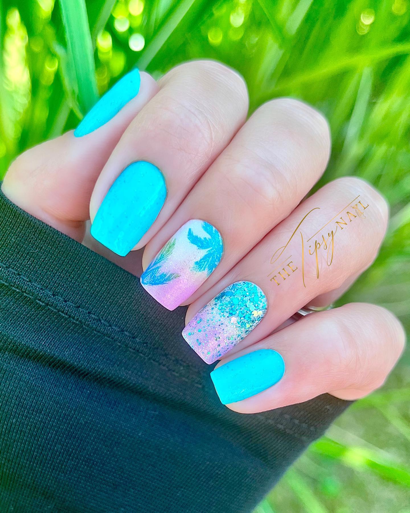 Shimmery turquoise nails with palm tree silhouettes. 