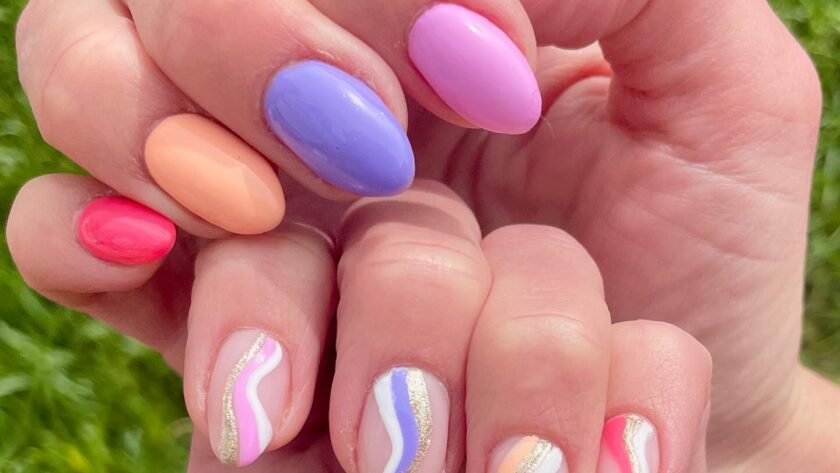 Two hands, one with solid painted nails in multiple spring colors, and the other hand with corresponding striped swirl designs.