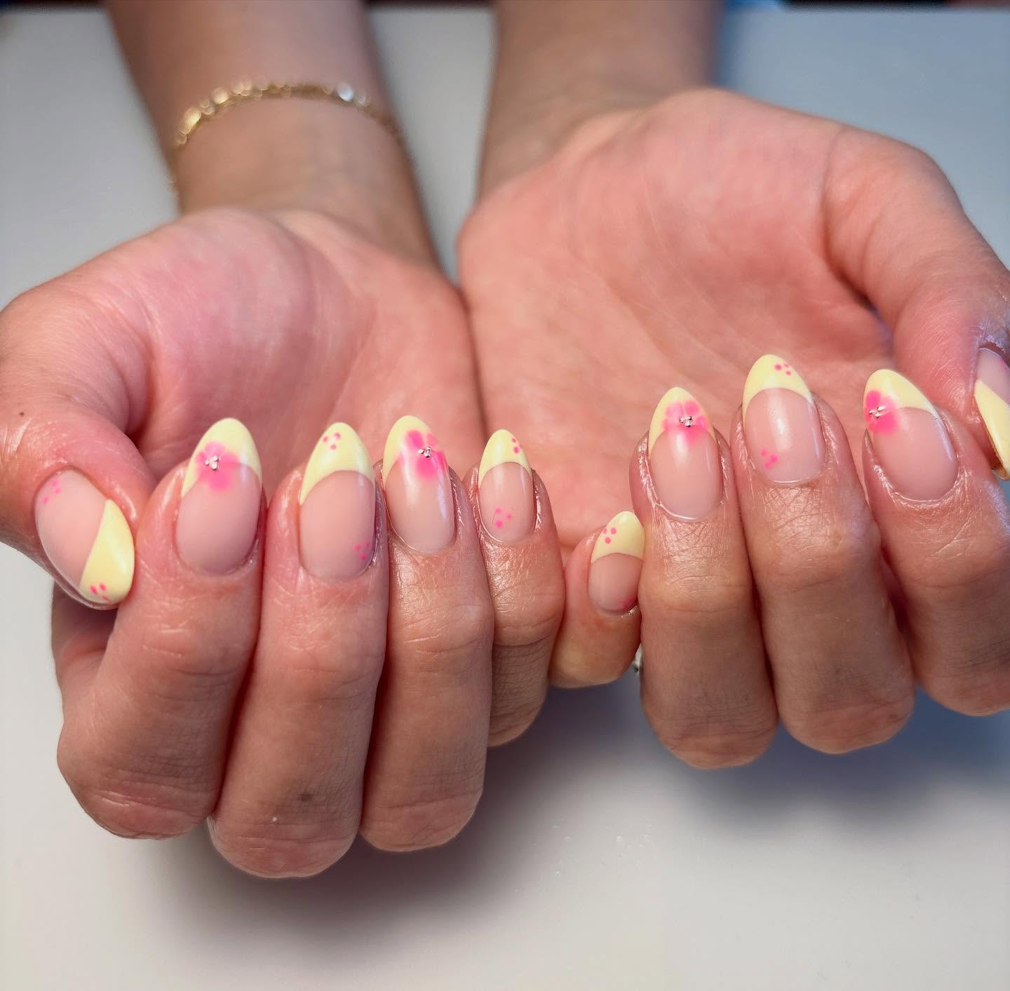 Yellow almond French tip nails with pink flowers.