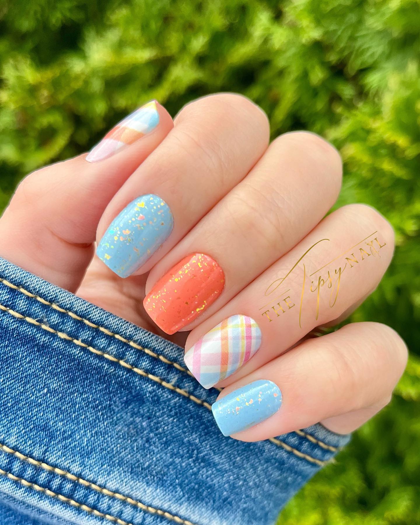 Blue and orange nails with glitter and a checker pattern accent nail.