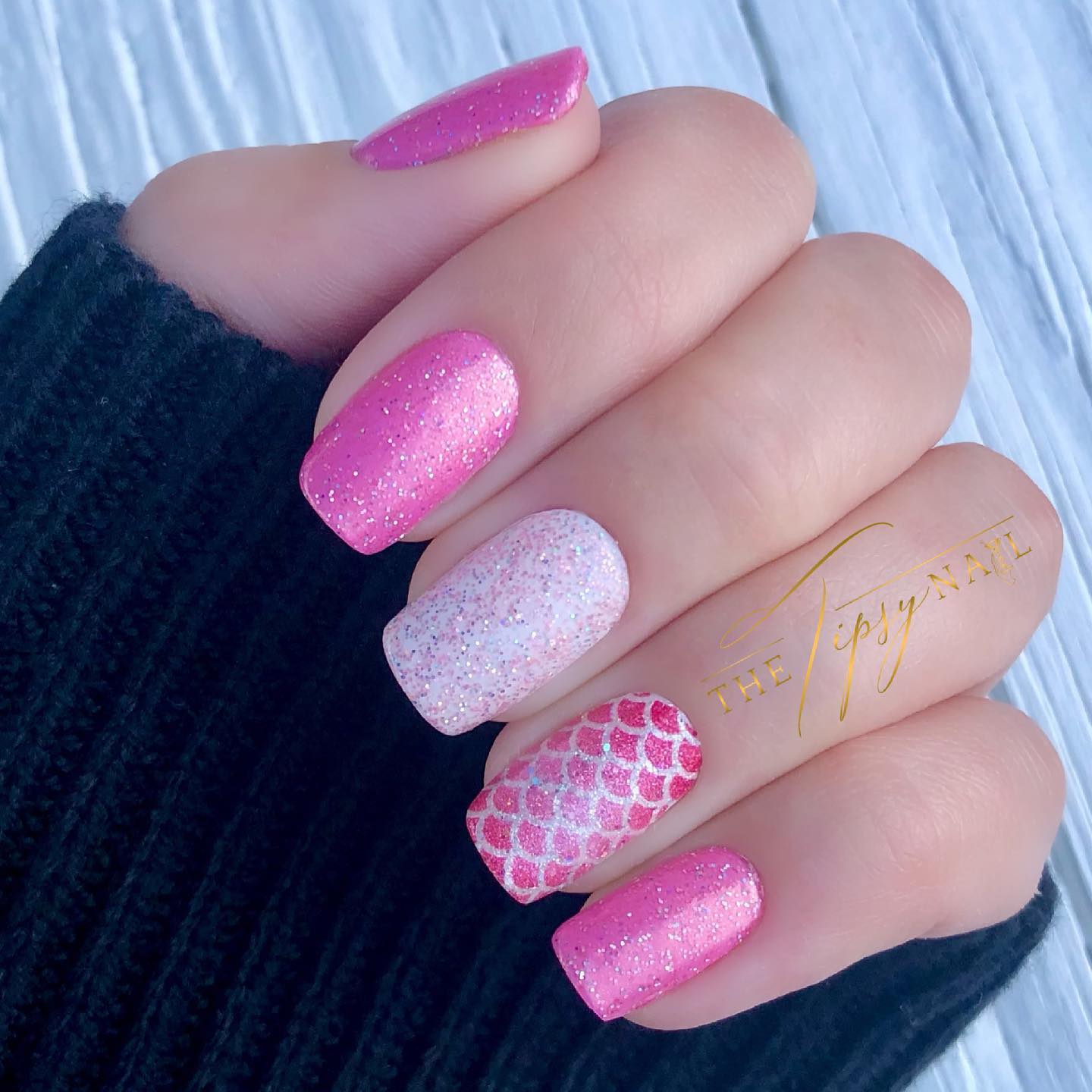 Glittery pink nails with a mermaid patter accent nail.