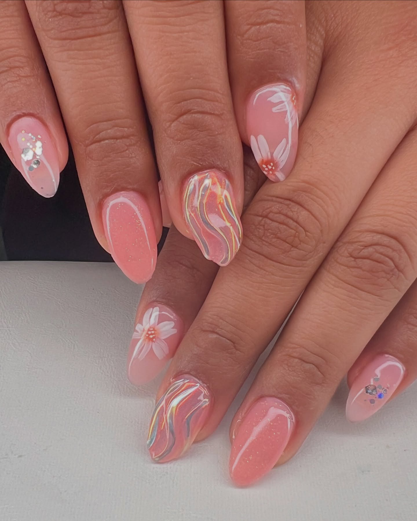 Clear pink nails with 3D swirl nail art and white flowers.