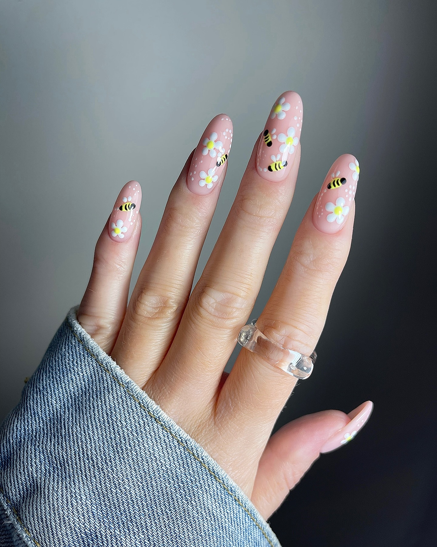Pale peach nails with white daisies and honey bee nail art.