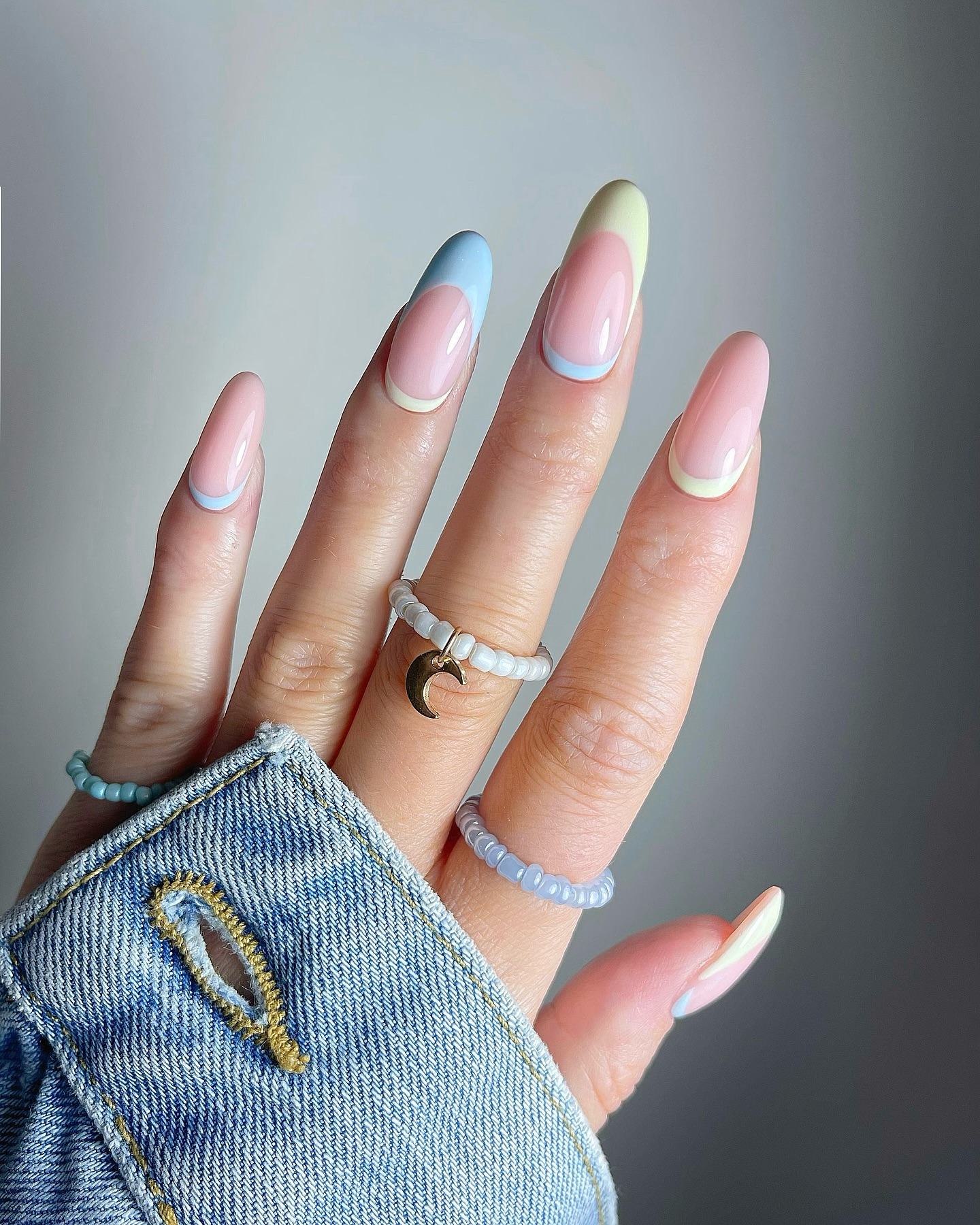 Almond pastel French tip nails with blue, green, and pale peach.