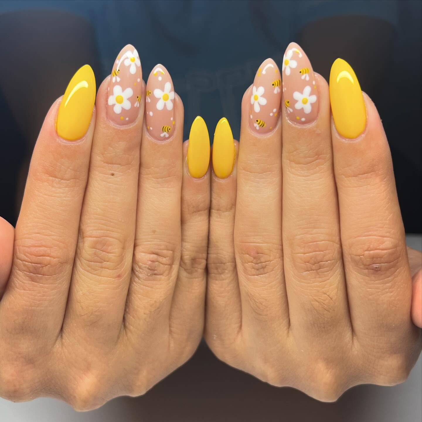 Golden yellow and nude nails with white daisies and bees.