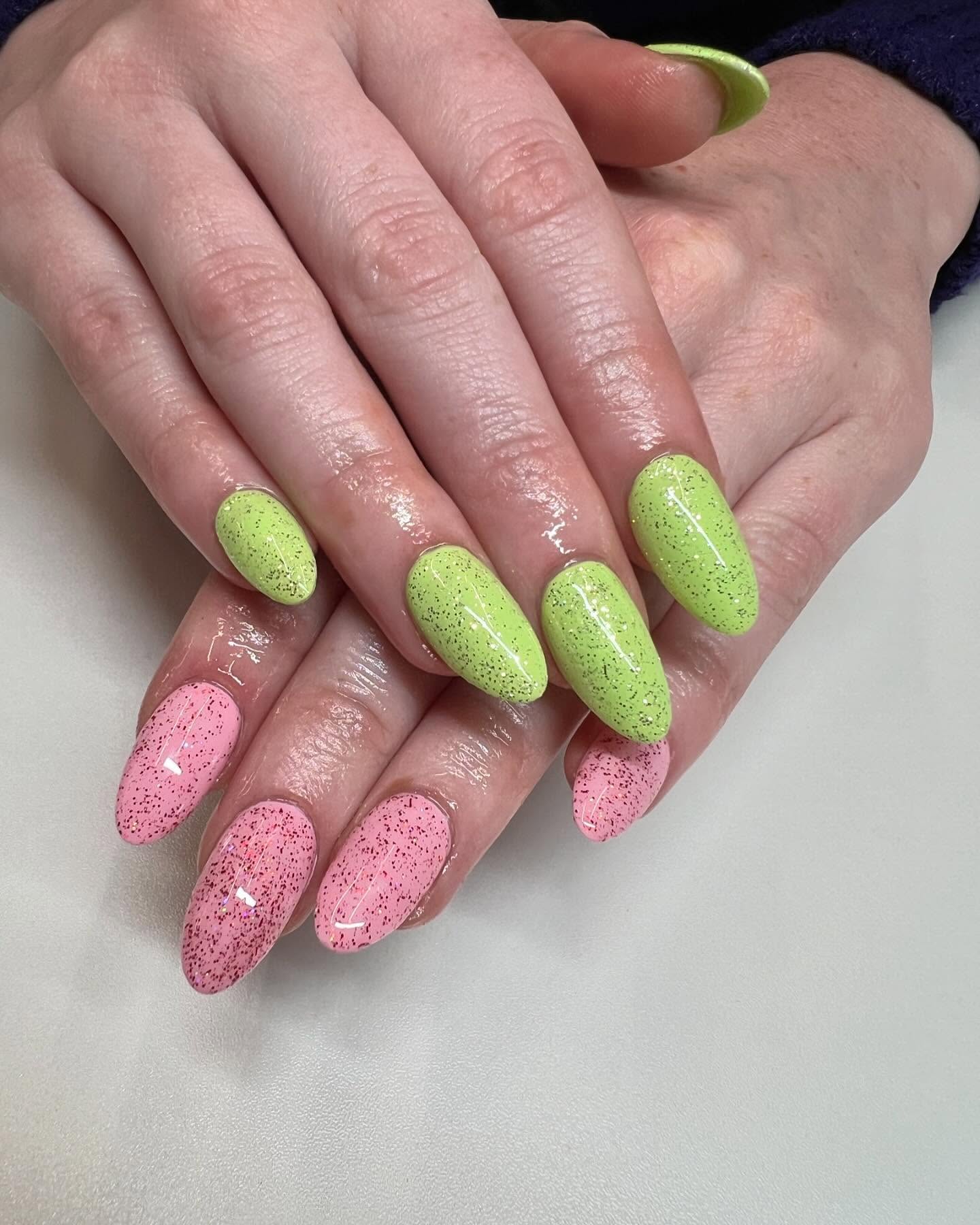 A manicure with pink glitter nails on one and and green glittery nails on the other.