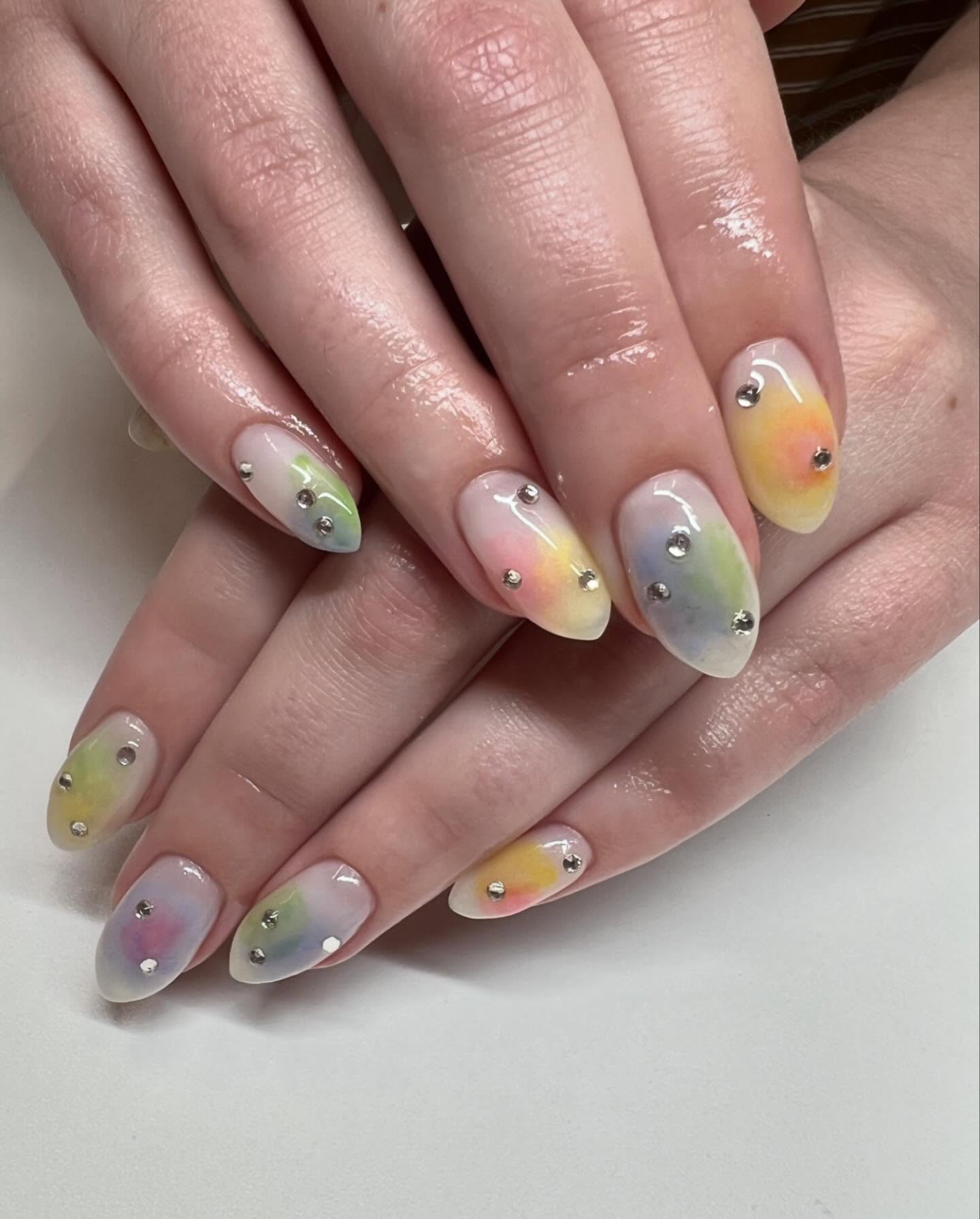 Pastel rainbow almond aura nails with clear round gems.