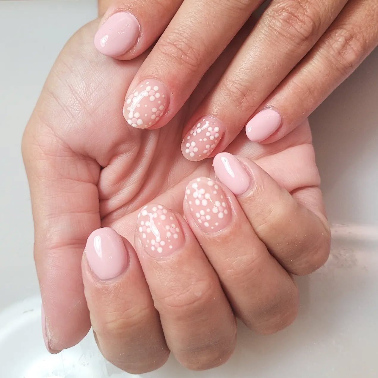 Nude nails with clear accent nails that have white and pink dots that from small flowers.