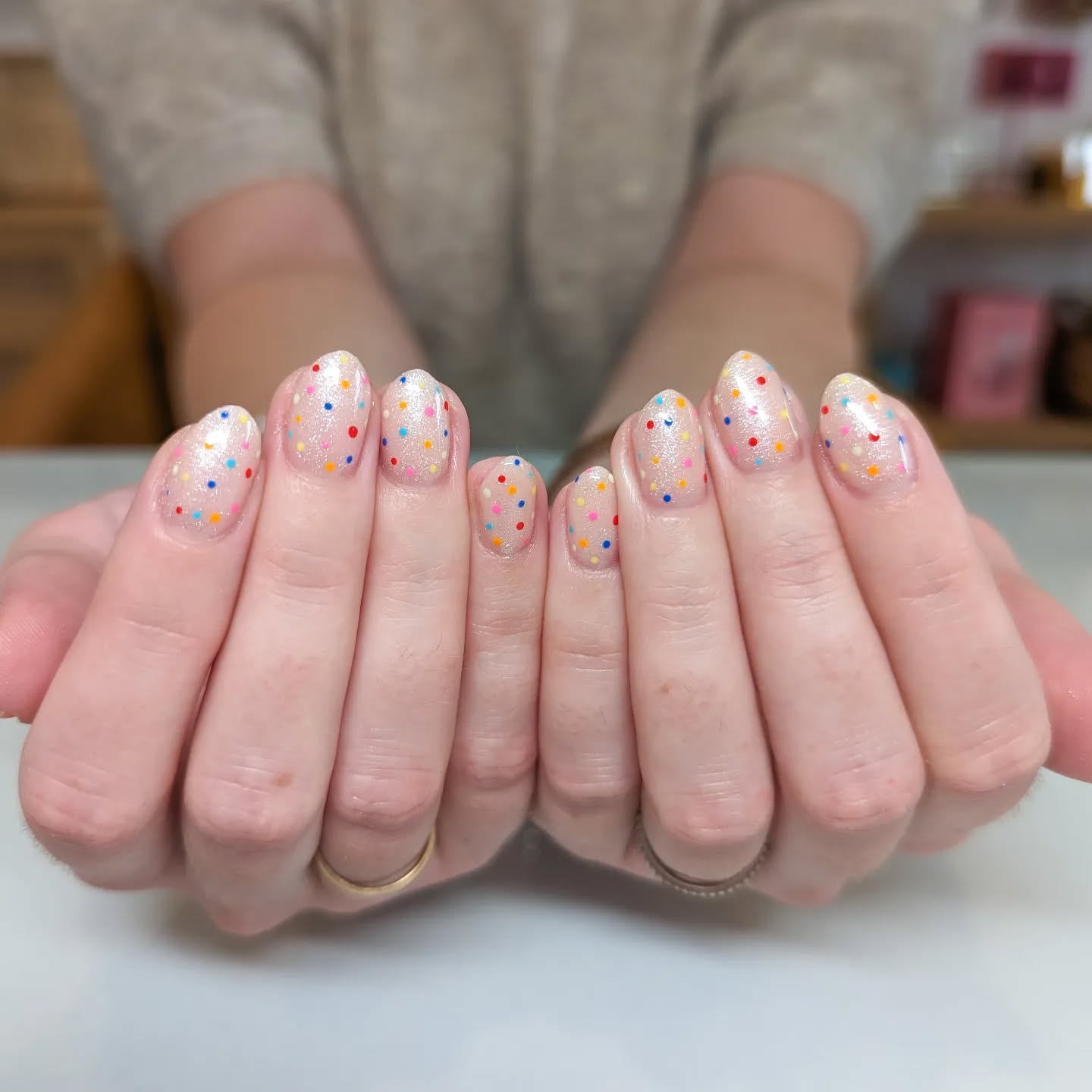 Shimmery white nails with mini polka dots in multiple colors.