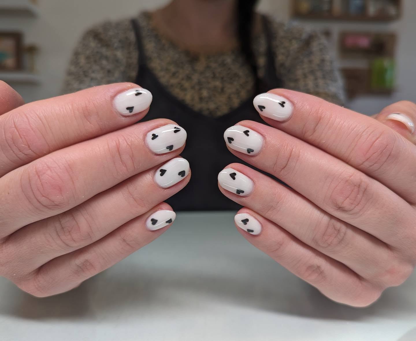 White almond nails with mini black hearts.