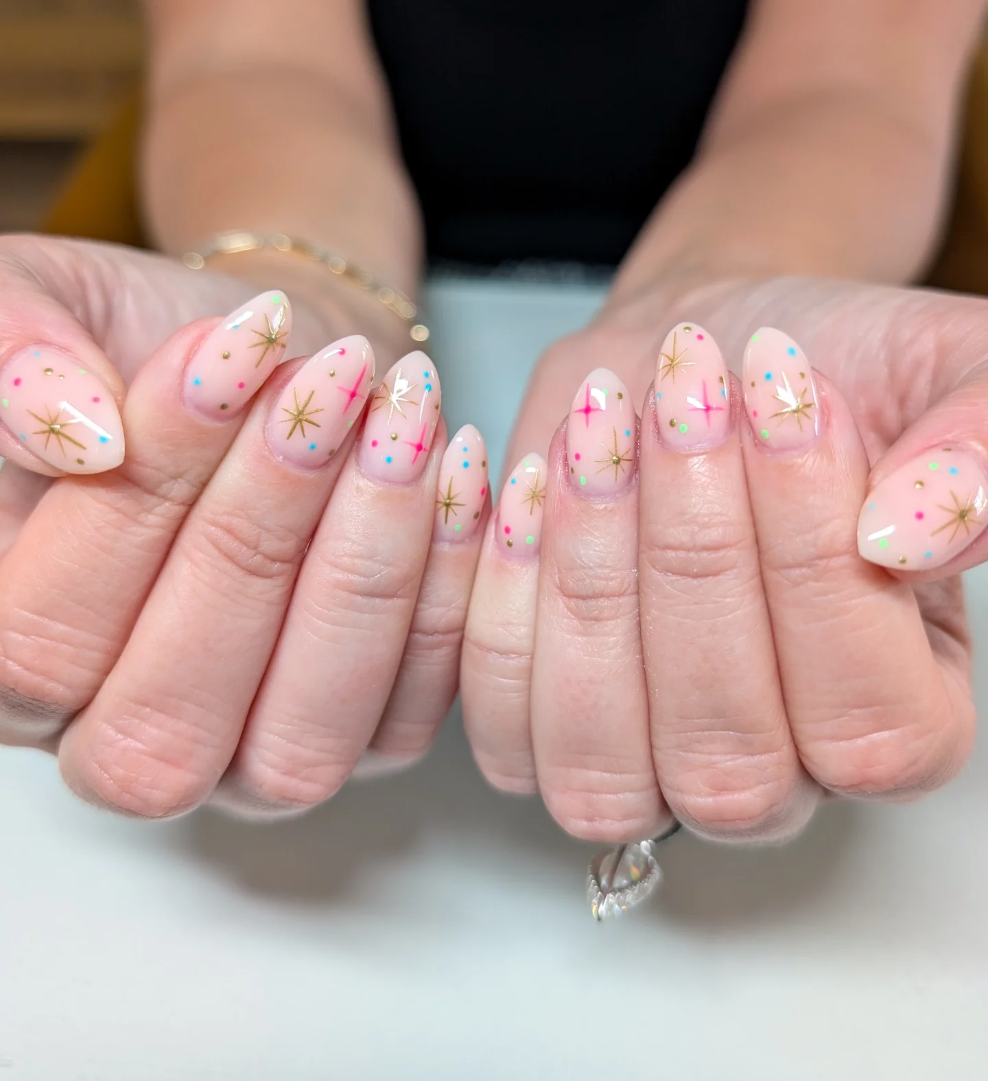 Nude nails with mini star designs in different colors.
