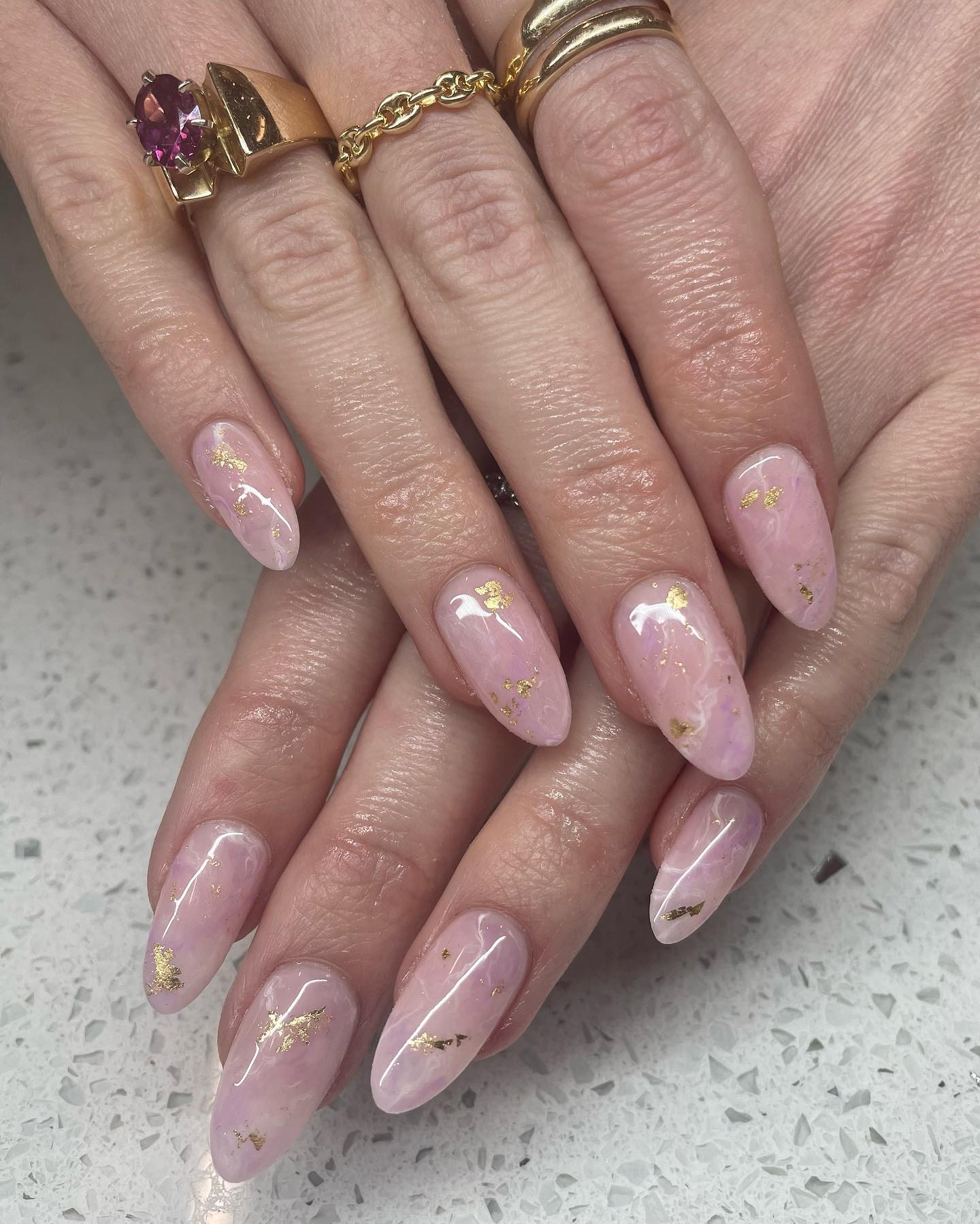 Marbled nude nails with shimmery milky white and gold swirls.
