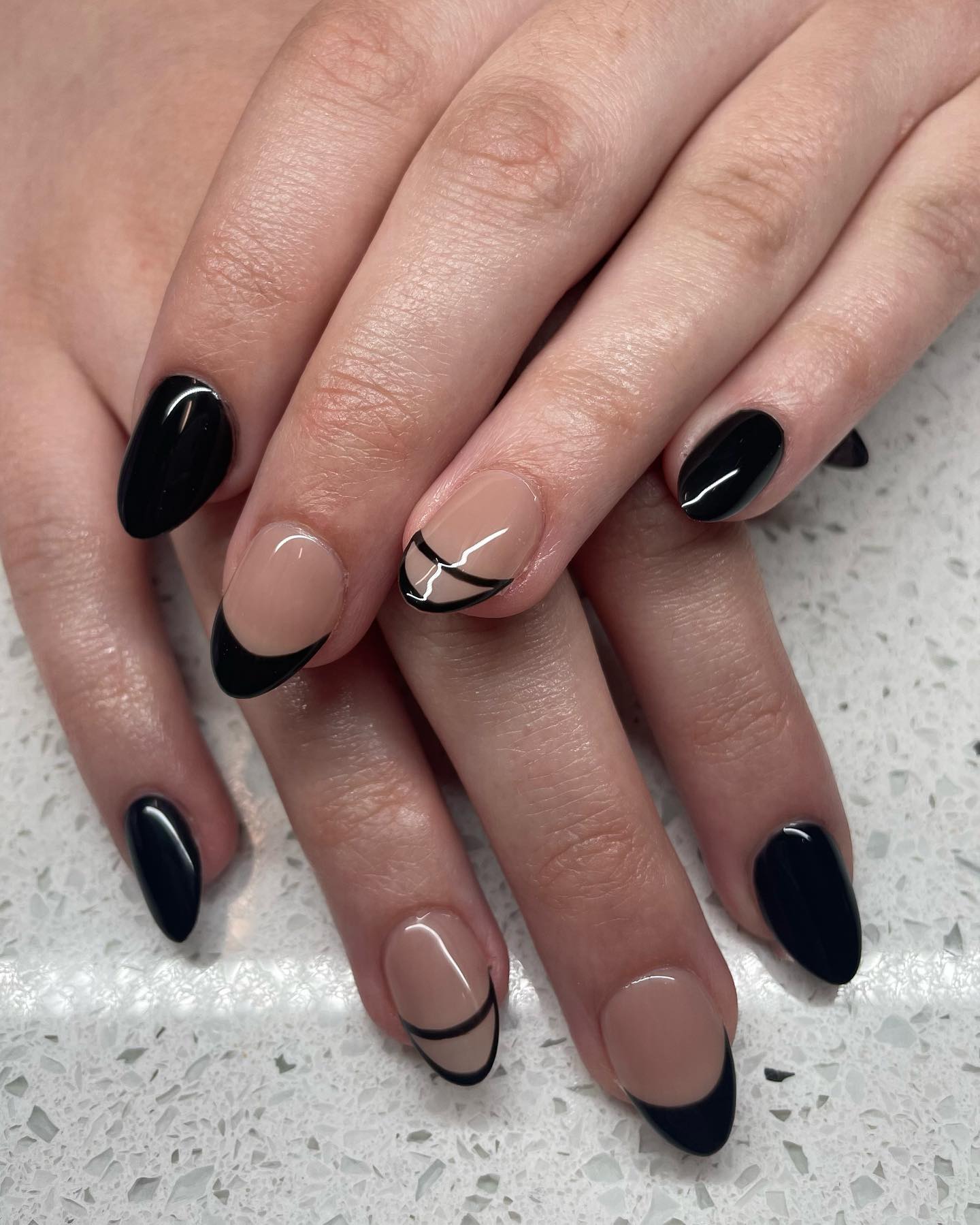 Black nails with nude accent nails that have either a black french tip or a french tip outlined in black.