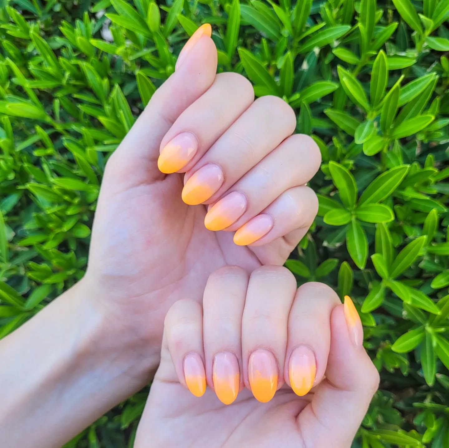 Nude almond nails with bright orange ombre tips.