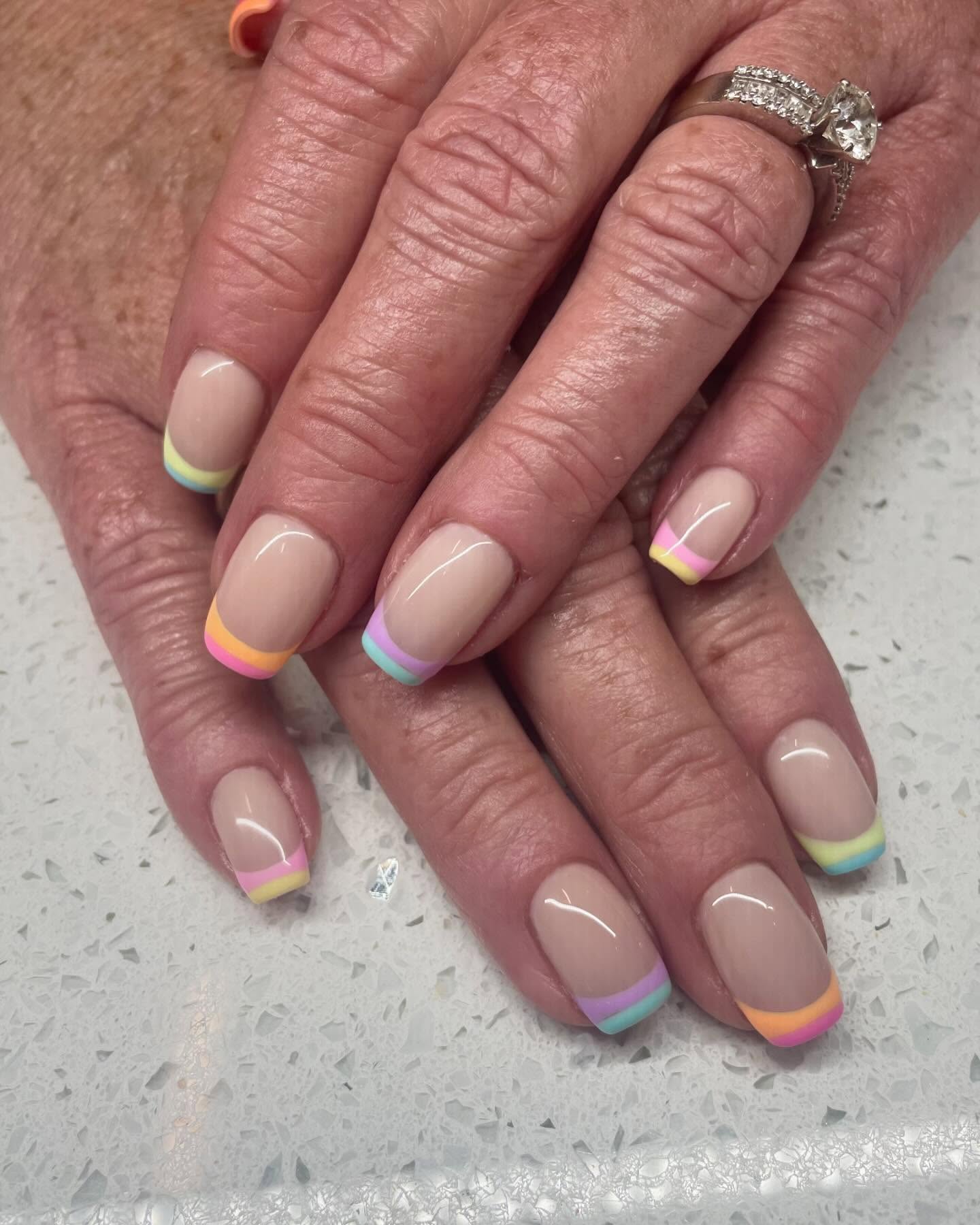 Nude nails with rainbow French tips.
