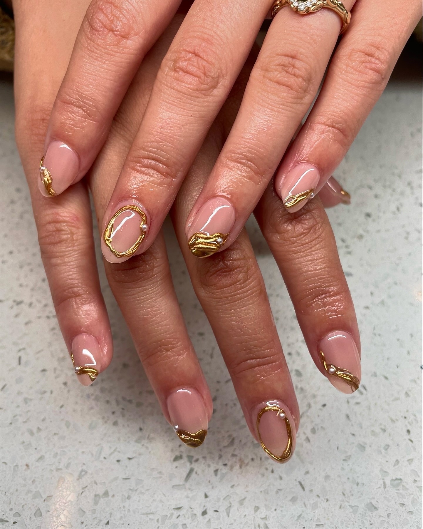 Nude nails with raised gold organic shapes.