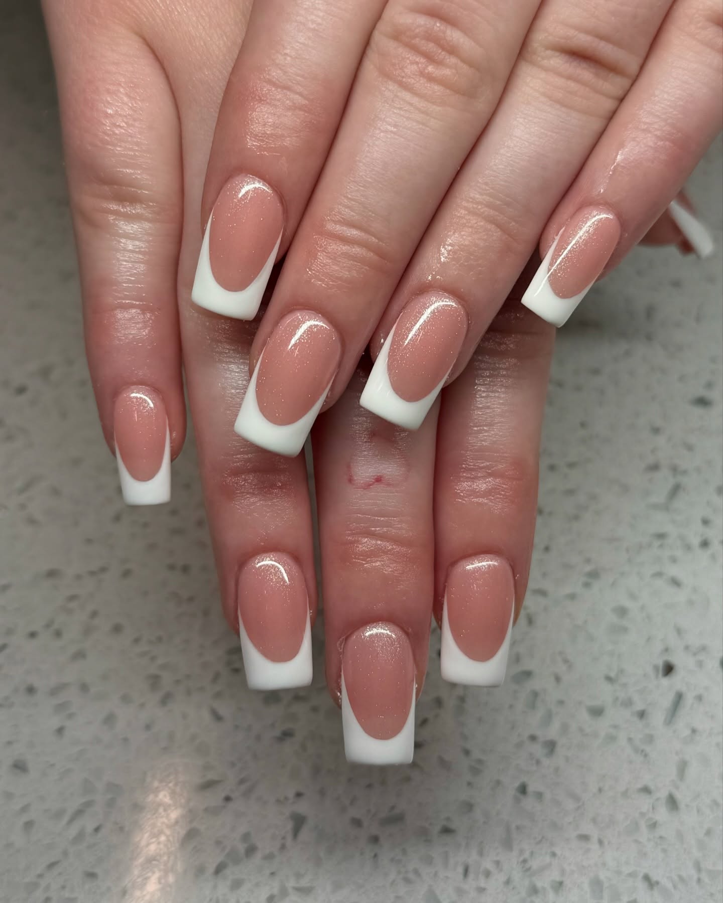 Shimmery peach nails with White French tips.