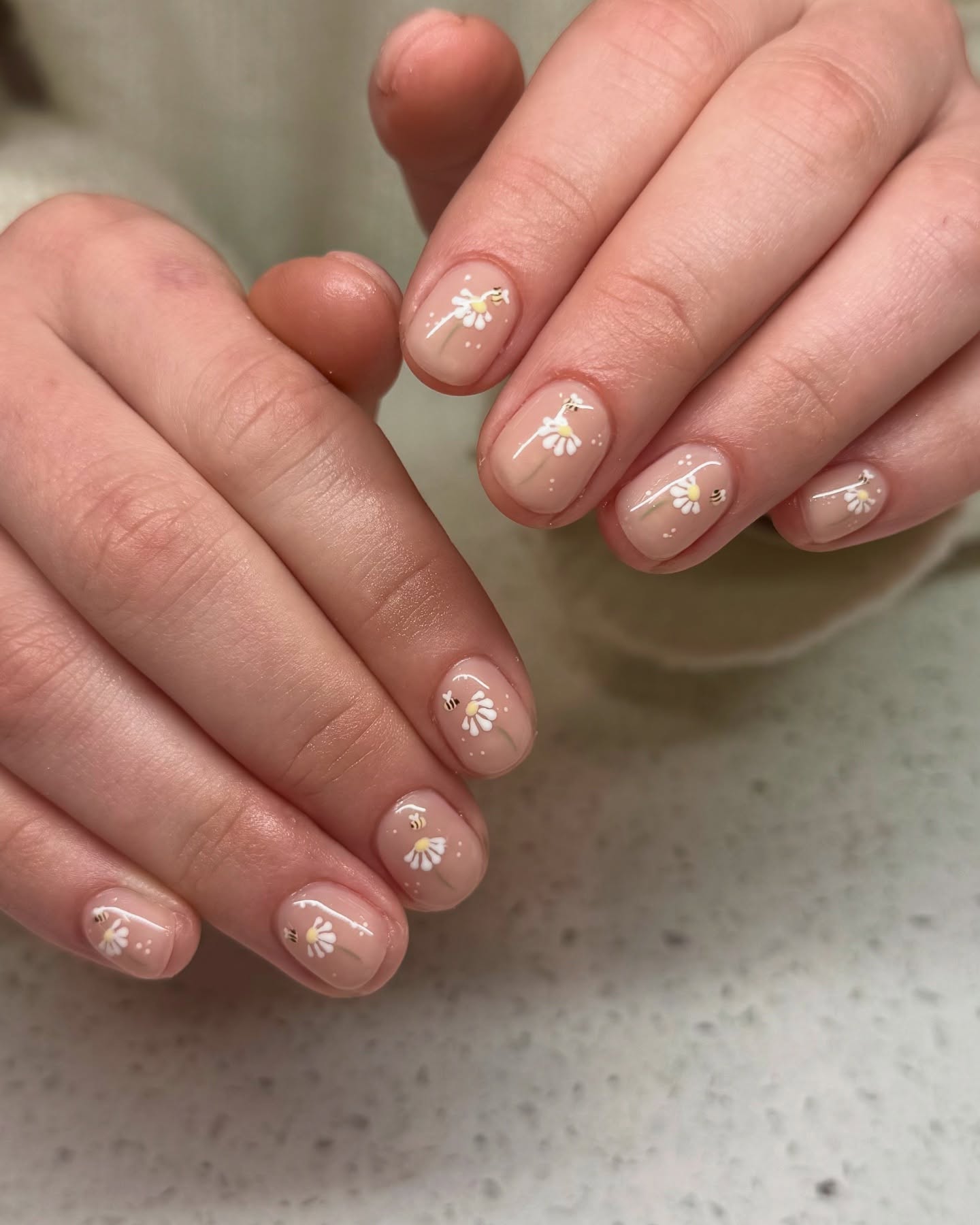 Nude nails with mini daisy flowers and bees.