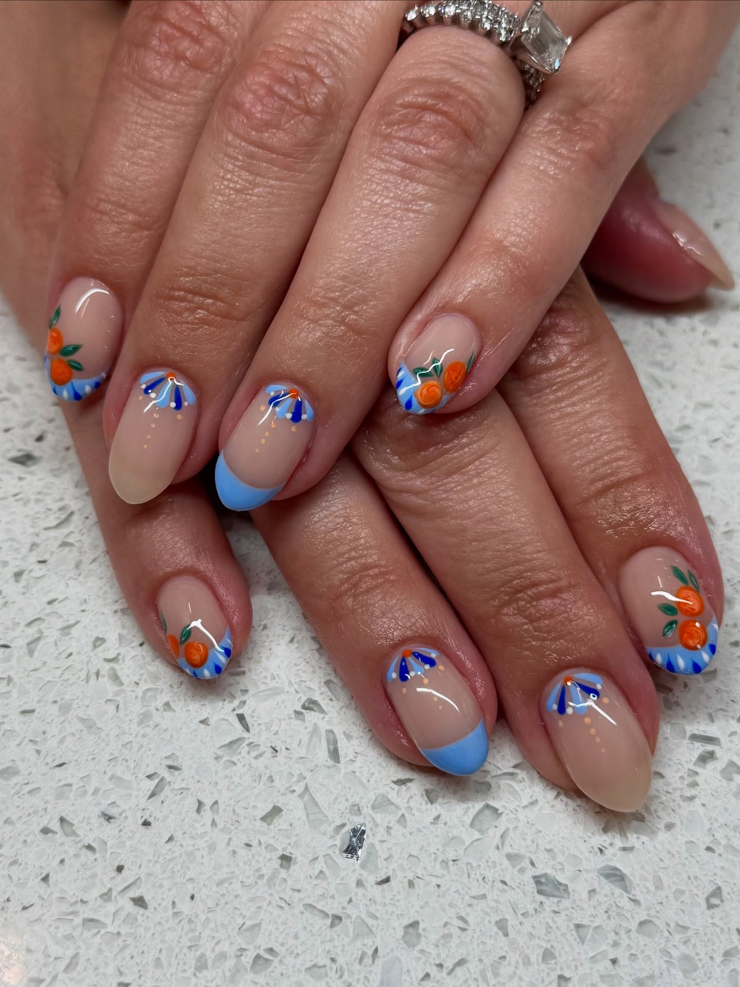 Nude nails with blue petal designs and cutie oranges.