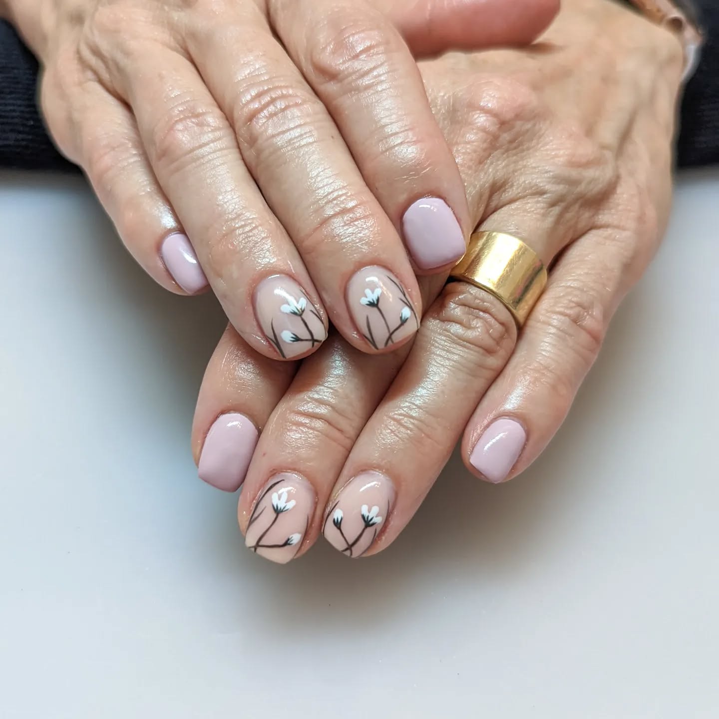 Blue pink nails with nude accents that have spring flowers on them.