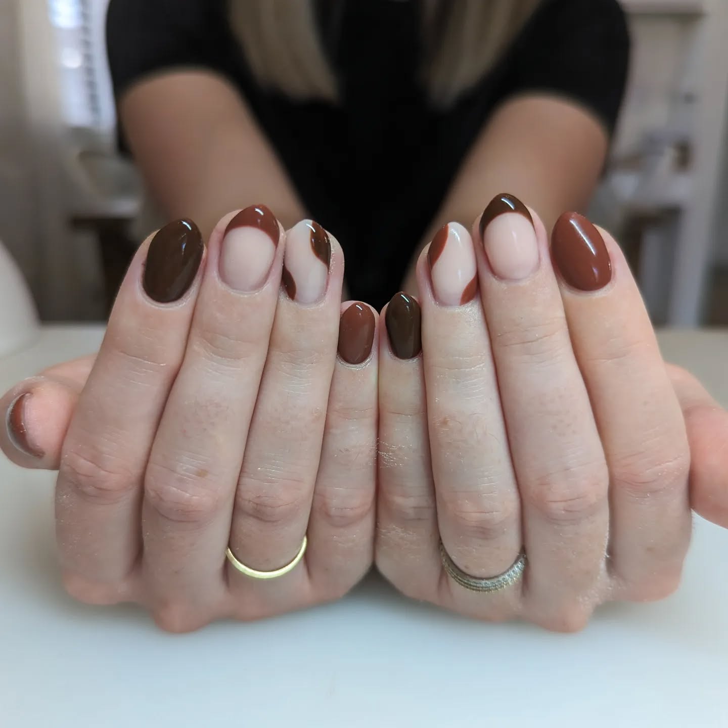 Nude nails with brown swirls or a French tip with solid brown accent nails in various shades.