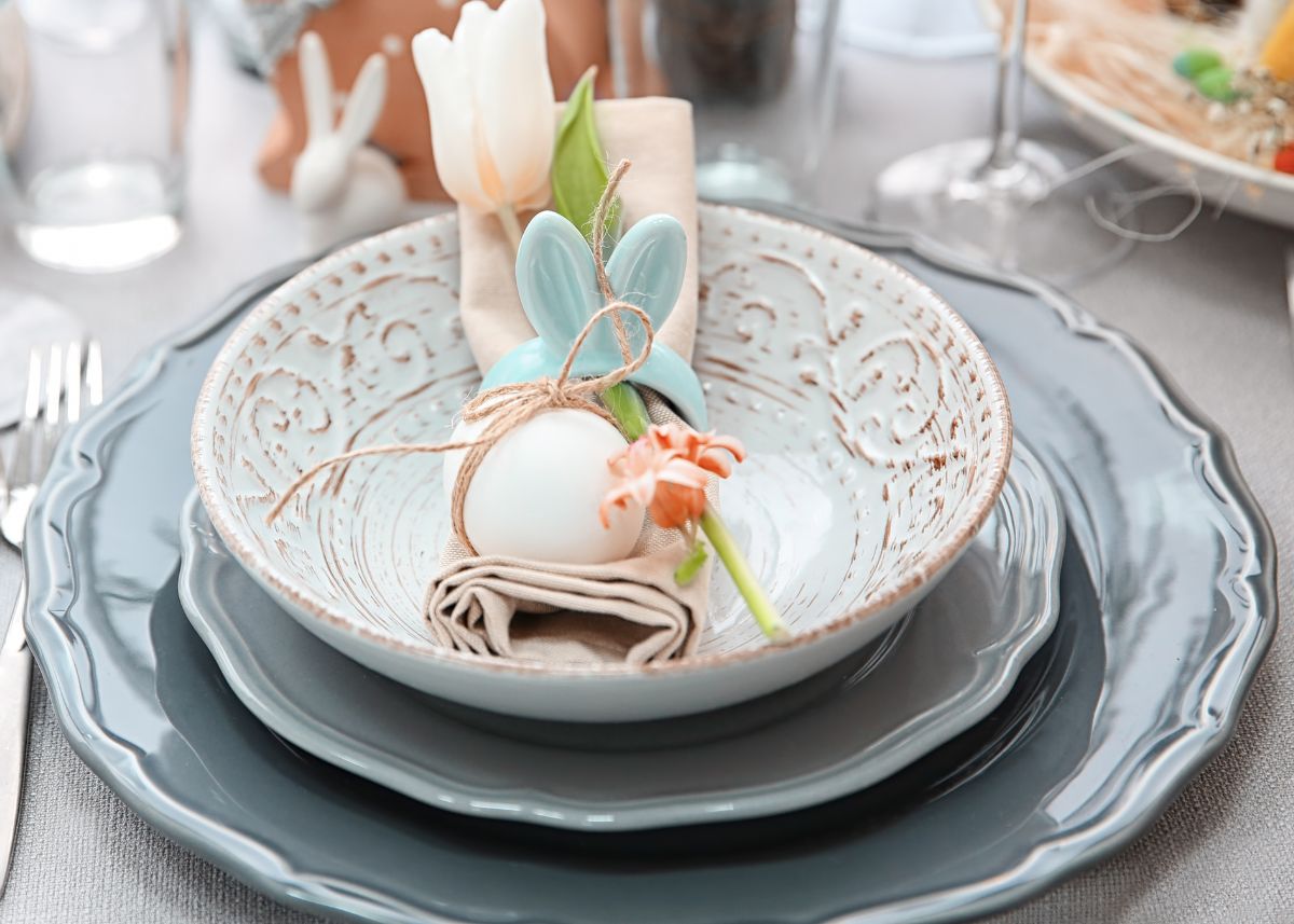 Blue Easter place setting with a cream napkin, blue Easter bunny ears napkin ring, and tulips.