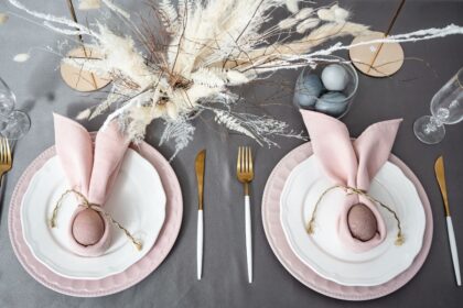 Pink and white place settings with brown eggs wrapped in pink napkins with twine.