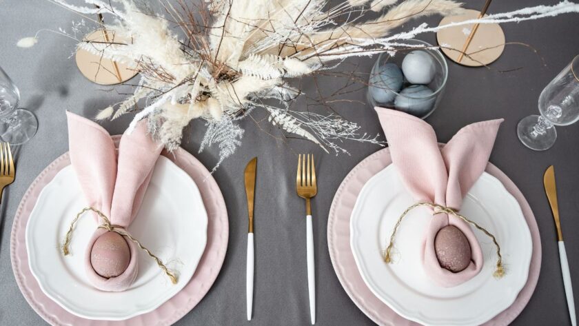 Pink and white place settings with brown eggs wrapped in pink napkins with twine.
