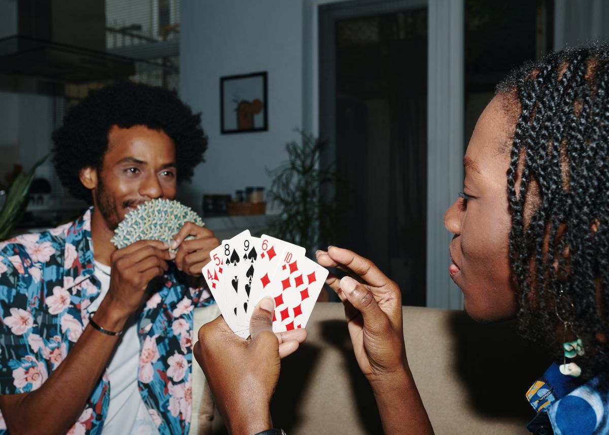 A couple playing cards with the cards fanned out in their hands.