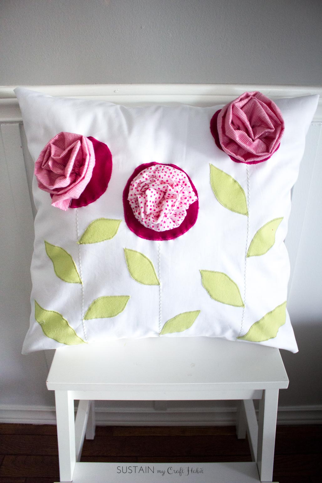 Homemade pillow with purple flowers and green leaves.