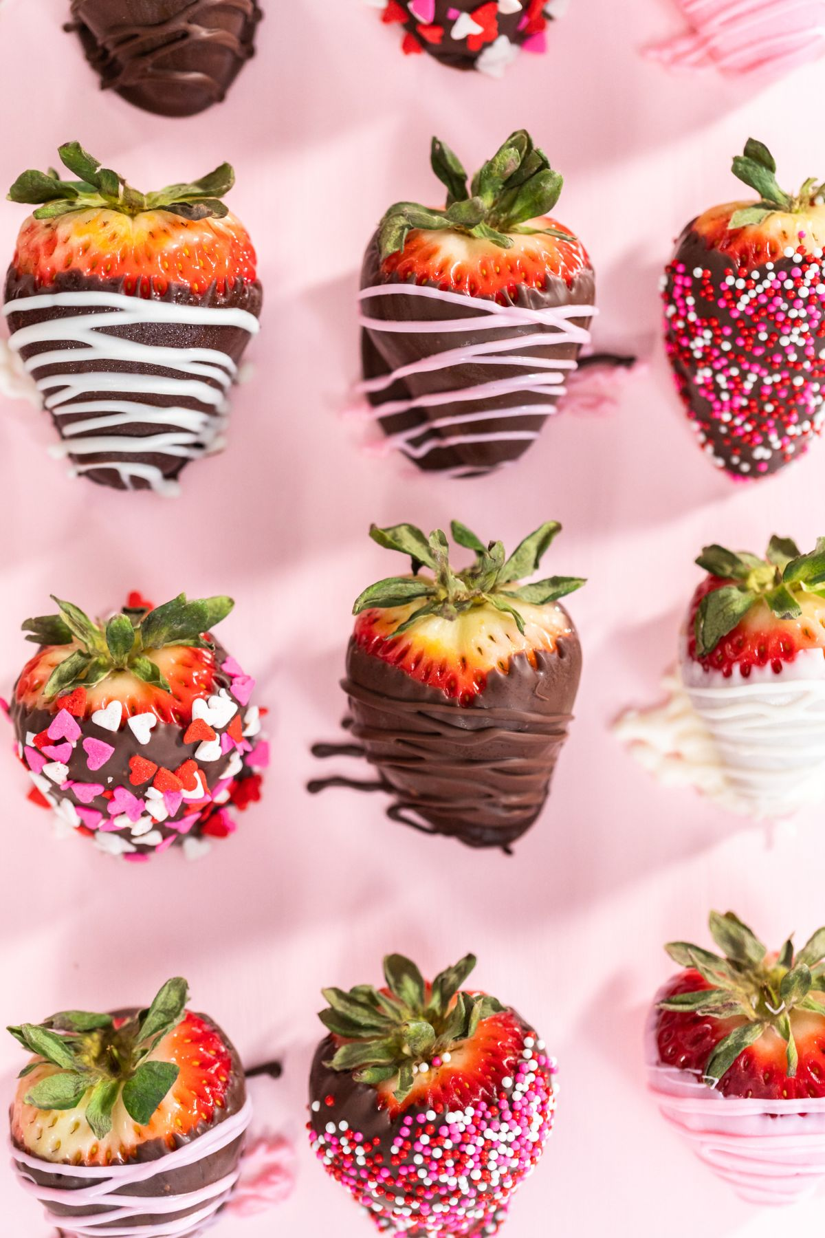 Homemade chocolate-dipped strawberries on a pink background.